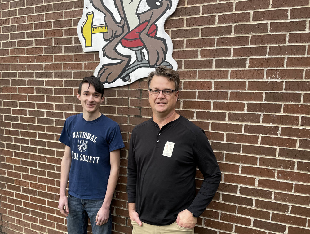a high school student and his teacher stand together