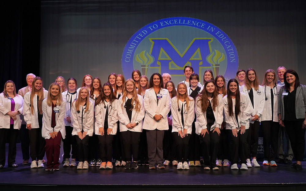 a photo of senior white coat students with Baxter Health staff