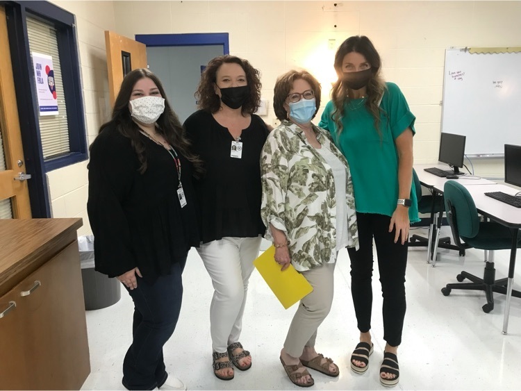 four women who are high school teachers stand together with face masks