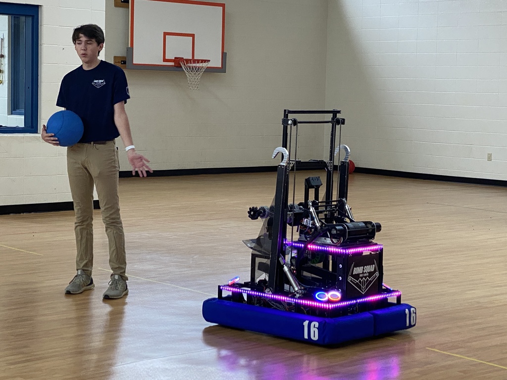 a teen shows a robot to kindergarten students
