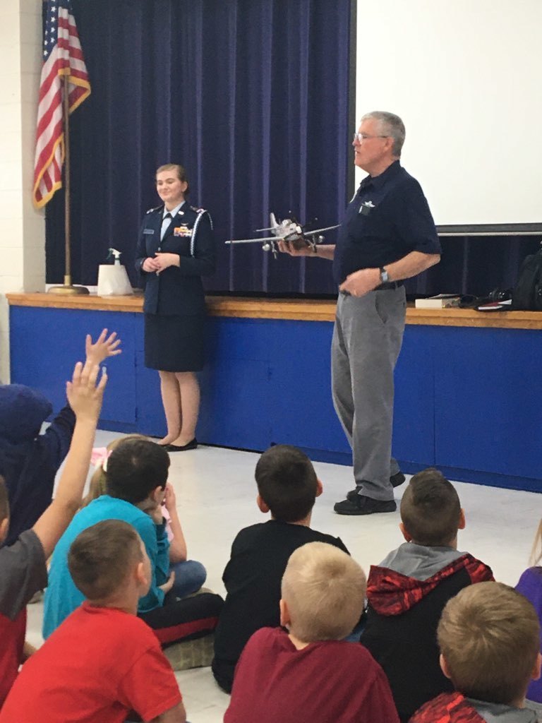 a man and woman presenting to an elementary school