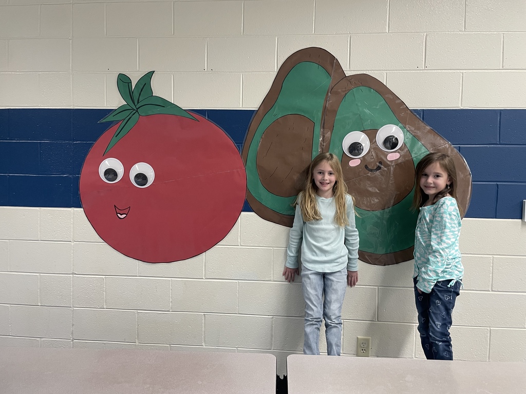 two young girls in a cafeteria with a tomato and avocado wall decoration