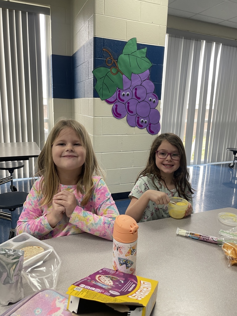two young girls in a cafeteria with a grape wall decoration