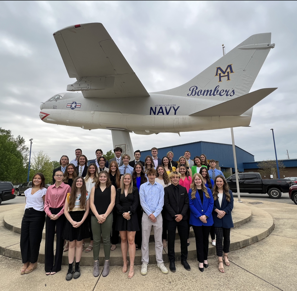 a group of students pose together in front of the bomber plane